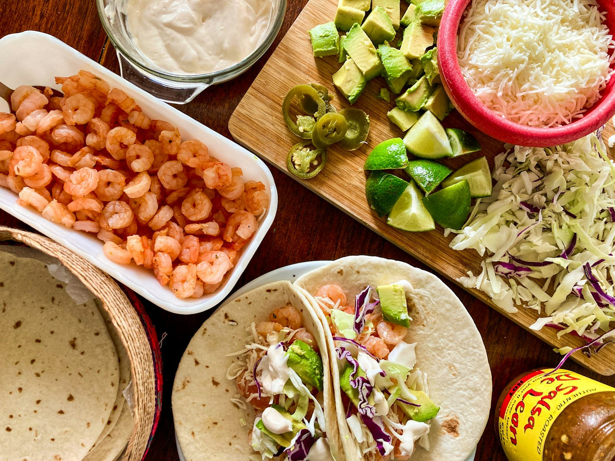 Grilled shrimp tacos with cabbage slaw, lime wedges and fresh toppings