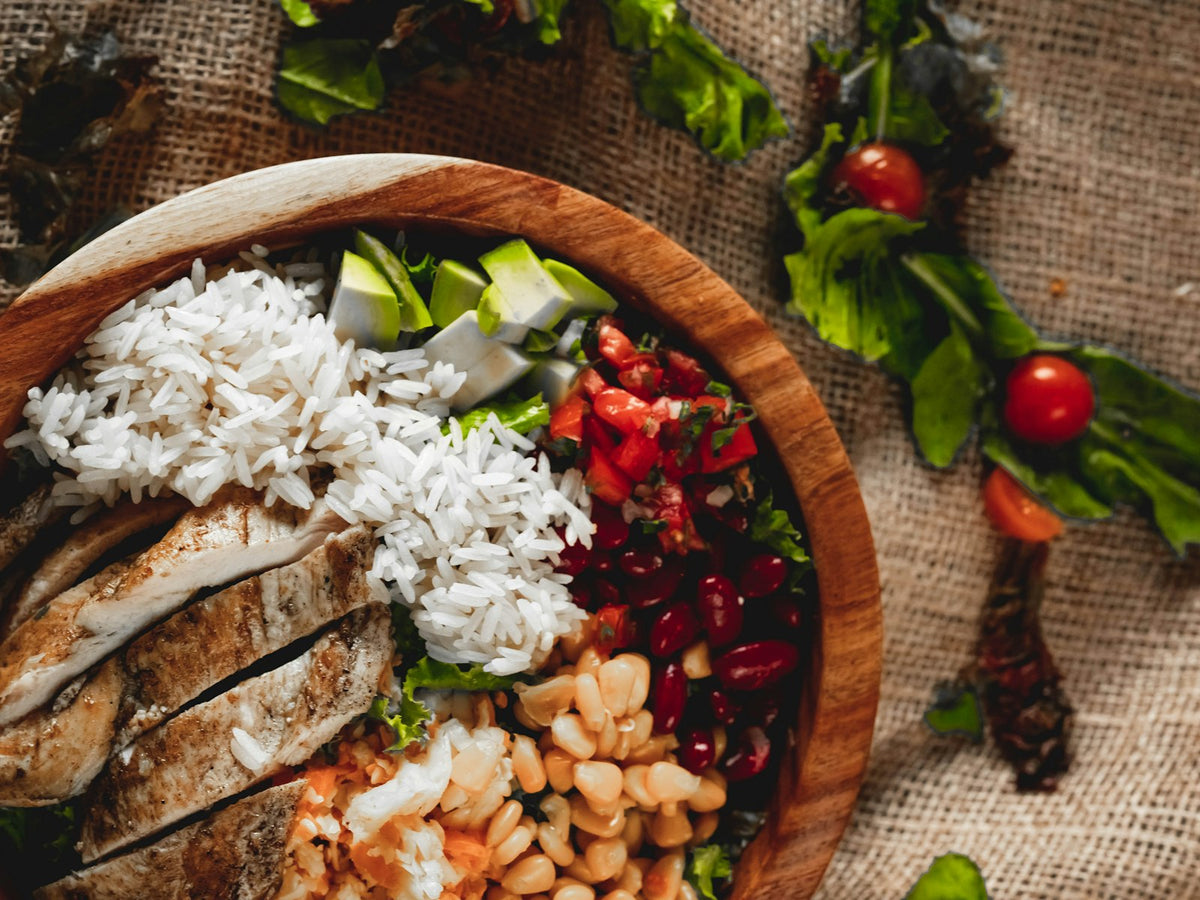 Chicken and rice bowl with vegetables, beans and fresh greens, illustrating a lemon-garlic chicken rice bowl serving